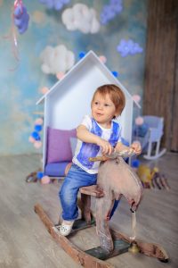 little boy playing on wooden horse