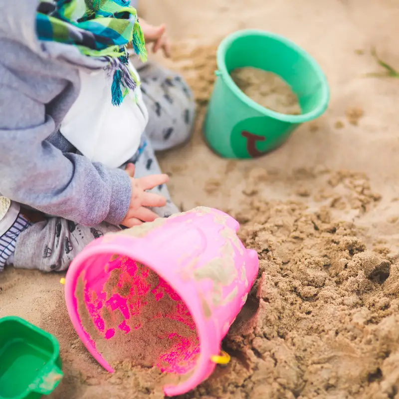 Sandcastles buckets in sandpit with child