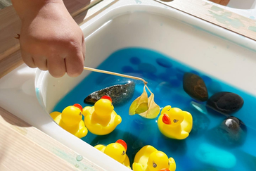 Boy trying to catch rubber duck on fishing game in amusement park