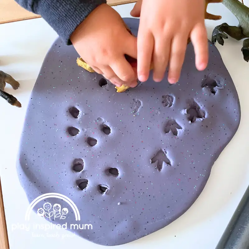 stamping dinosaur footprints in play dough