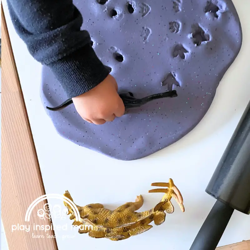 stamping dinosaur footprints in play dough