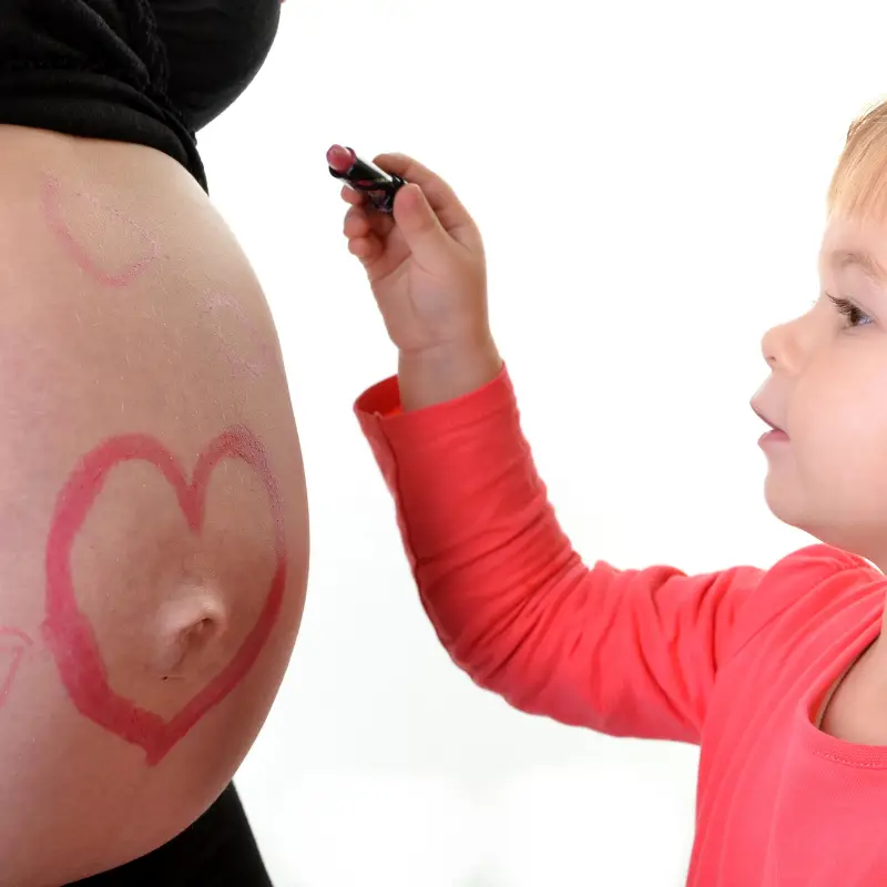 Toddler drawing on mums pregnant tummy