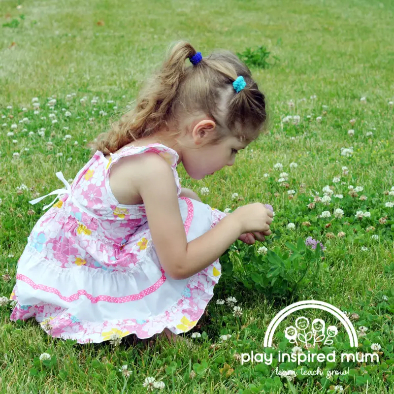 best hair tie for babies and toddlers girl playing in grass with clover blossoms
