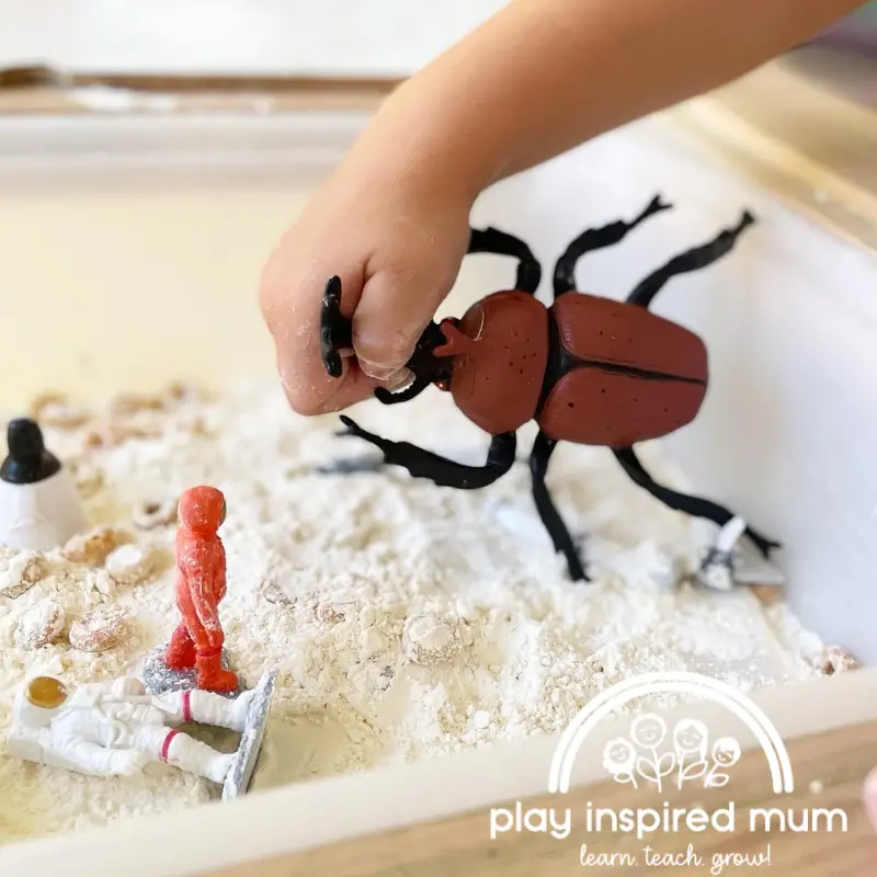 space themed sensory bin with insect